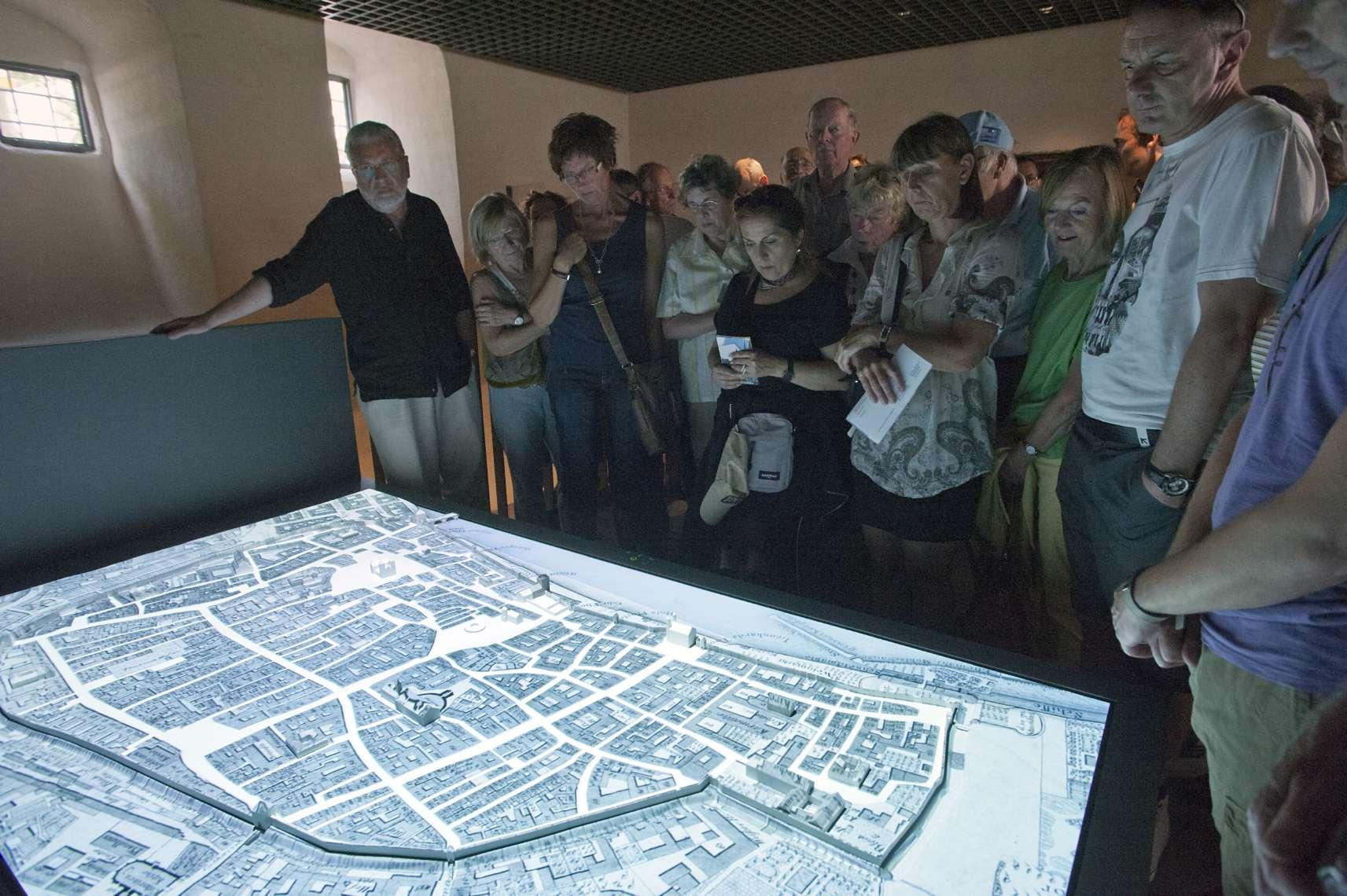 Eine Personengruppe betrachtet einen digitalen Stadtplan Frankfurts.
