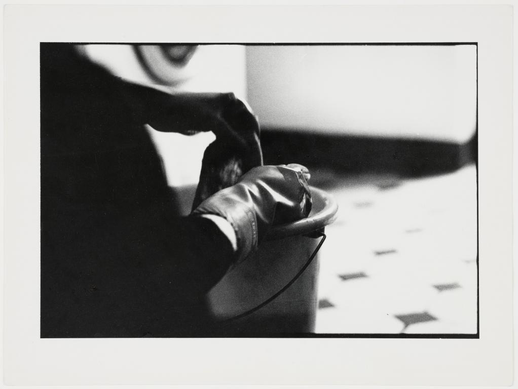 Schwarz-weiß-Bild, Nahaufnahme der Hände einer Person über einem Putzeimer