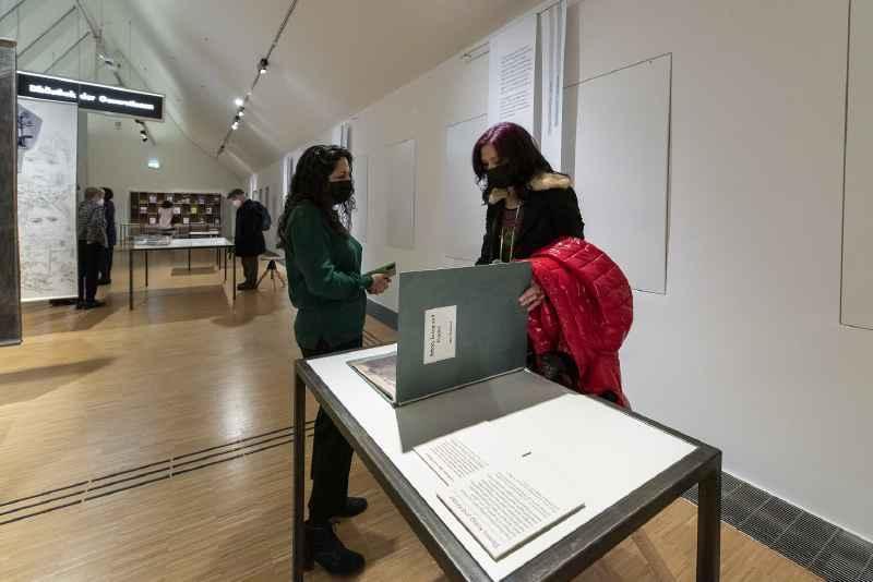 Zwei Frauen stehen vor einem Ausstellungsbeitrag und unterhalten sich