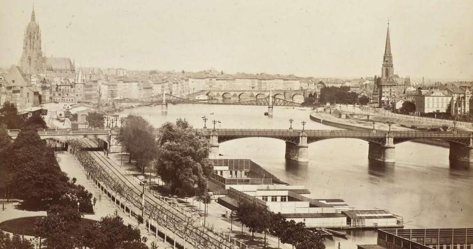 Das Schwarz-Weiß-Foto ist eine Stadtansicht Frankfurts. Man sieht Main, drei Brücken, den Dom und Sachsenhausen. 