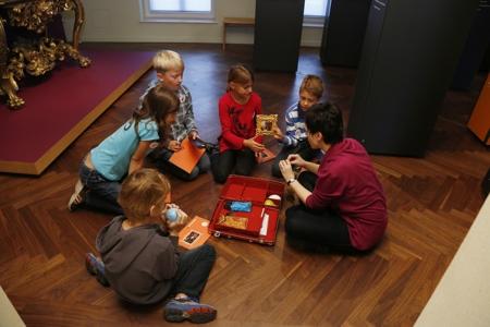 Kinder spielen mit in der Ausstellung Glock mit kleinen Nachbildungen