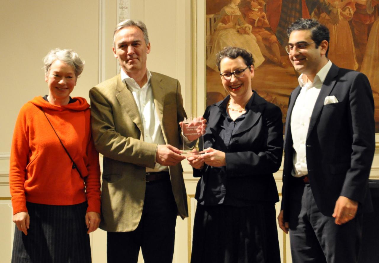 Das Foto zeigt vier Personen, die einen gläsernen Preis in ihrer Mitte halten. 