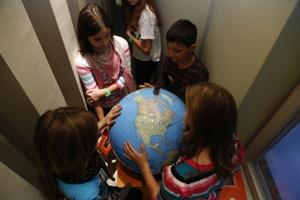 Kinder stehen um einen Globus und betrachten die Karte