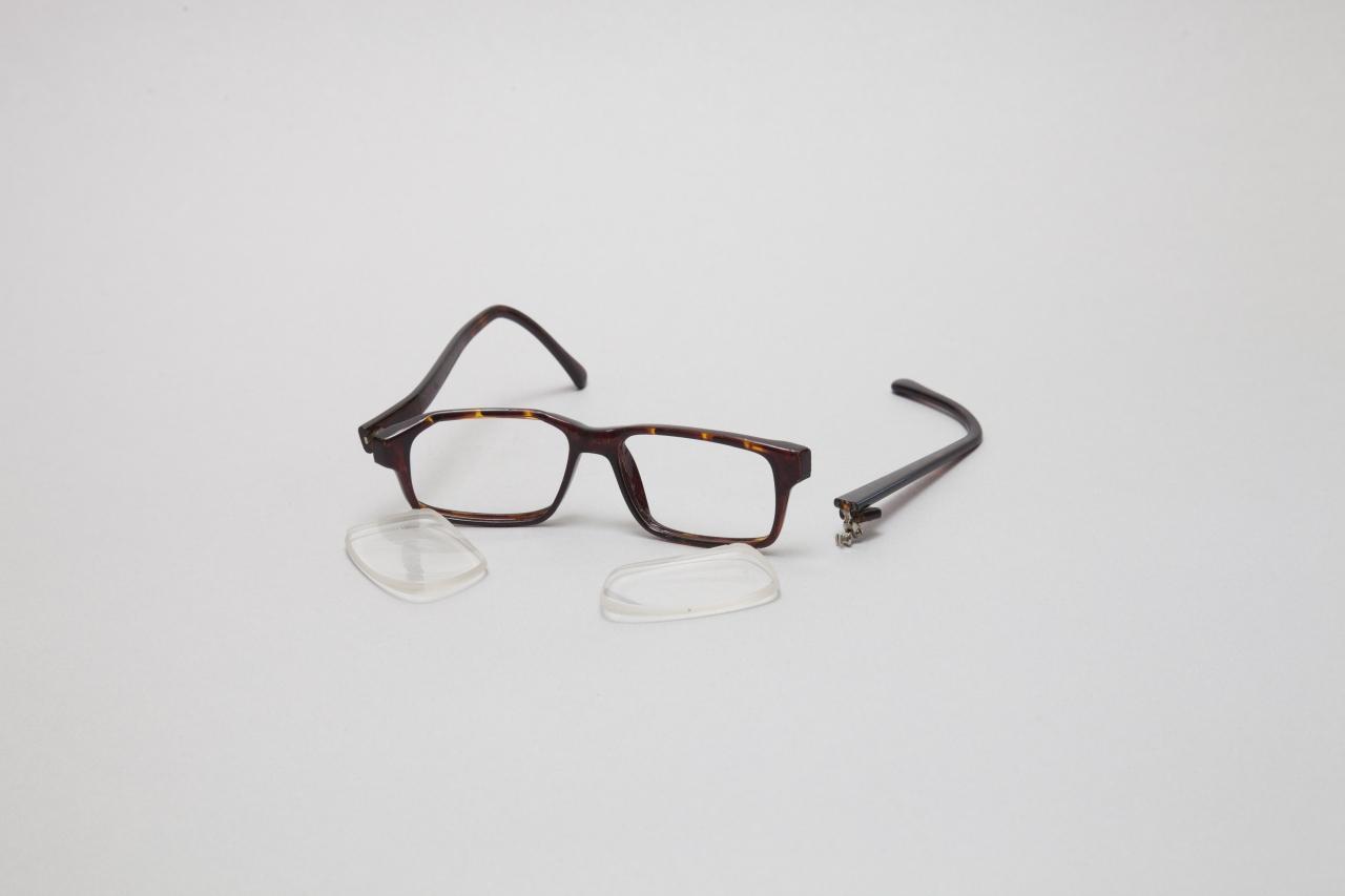 Das Foto zeigt eine kaputte Brille mit gebrochenen Bügeln und herausgefallenen Gläsern
